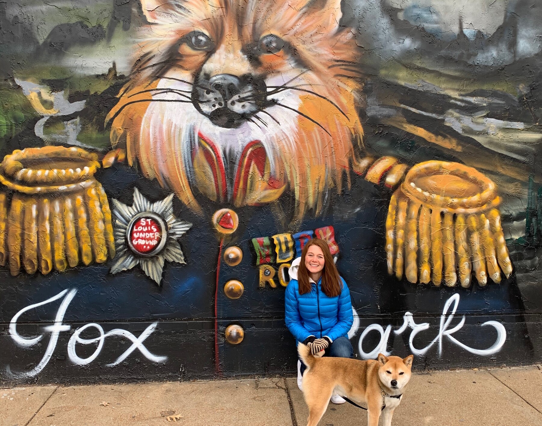 Dr. Magic Wade pictured with her dog in front of a painted mural of a fox on a brick wall