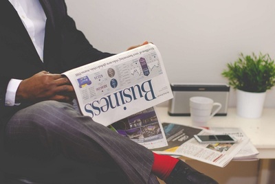 Photo of an African American man reading a business newspaper at a desk