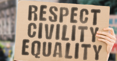 Photo of a hand holding up a cardboard sign saying "Respect, Civility, Equality"