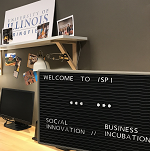 Sign with "Welcome to iSPI.  Social Innovation.  Business Incubation" in front of desk at the Innovate Springfield office